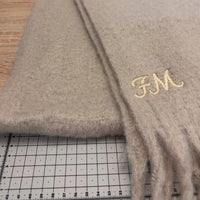 Load image into Gallery viewer, Beige fabric with gold monogram on a wooden surface next to a ruler
